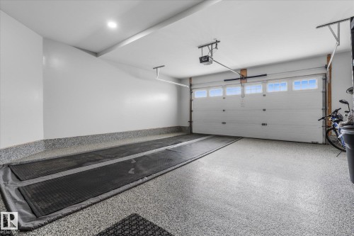 Spacious garage featuring a finished epoxy floor, white paneled garage door with windows, automatic garage door opener, and recessed ceiling lighting - 6 Sedona Place, Fort Saskatchewan, AB - Indoor Photo Showing Garage