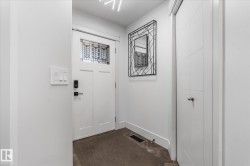 Entryway featuring a white paneled door with leaded glass transom, black smart lock hardware, and a modern ceiling light fixture - 