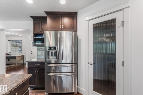Stainless steel French door refrigerator set within dark wood cabinetry - 6 Sedona Place, Fort Saskatchewan, AB - Indoor Photo Showing Kitchen With Stainless Steel Kitchen