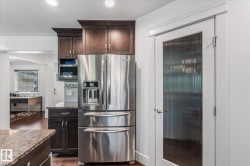 Stainless steel French door refrigerator set within dark wood cabinetry - 