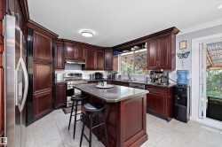 Kitchen featuring rich wood cabinetry, stainless steel appliances, a center island with seating, recessed lighting, and tile flooring - 