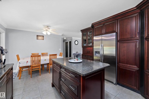 Kitchen featuring dark wood cabinetry, a central island with a stone-finish countertop, a stainless steel refrigerator, and recessed lighting - 53257 Rge Road 211, Rural Strathcona County, AB - Indoor Photo Showing Kitchen