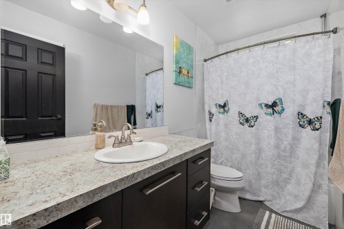 Bathroom vanity with an integrated oval sink, a speckled light-toned countertop, and dark wood-finish cabinetry featuring brushed nickel hardware - 53257 Rge Road 211, Rural Strathcona County, AB - Indoor Photo Showing Bathroom