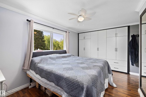 Bedroom with wood-finish flooring, a ceiling fan, and a large window - 53257 Rge Road 211, Rural Strathcona County, AB - Indoor Photo Showing Bedroom