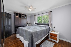 Bedroom featuring wood-finish flooring, a ceiling fan with integrated lighting, and crown molding - 