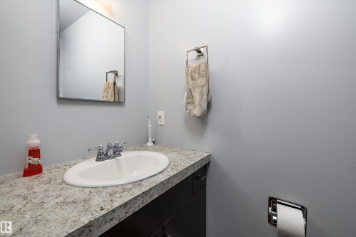 Bathroom vanity featuring an oval undermount sink, dual-handle faucet, and a light-toned patterned countertop - 53257 Rge Road 211, Rural Strathcona County, AB - Indoor Photo Showing Bathroom