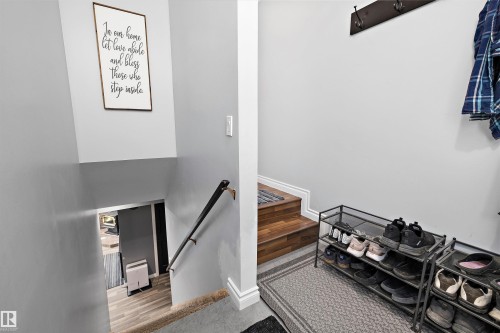 Split-level entryway featuring wood-finish stairs, a metal handrail, and light gray wall paint - 53257 Rge Road 211, Rural Strathcona County, AB - Indoor Photo Showing Other Room