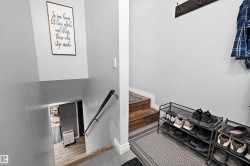Split-level entryway featuring wood-finish stairs, a metal handrail, and light gray wall paint - 
