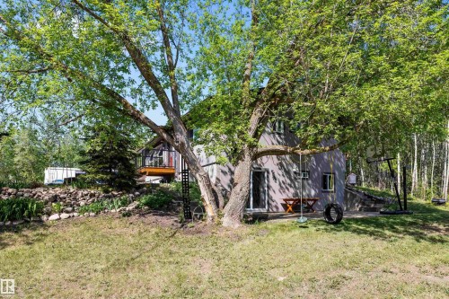 Lush green trees framing a multi-level property with a lower-level walkout and an upper-level deck - 53257 Rge Road 211, Rural Strathcona County, AB - Outdoor