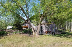 Lush green trees framing a multi-level property with a lower-level walkout and an upper-level deck - 
