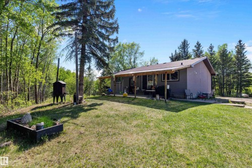 Expansive backyard featuring a manicured lawn, established landscaping, and a covered patio area - 53257 Rge Road 211, Rural Strathcona County, AB - Outdoor