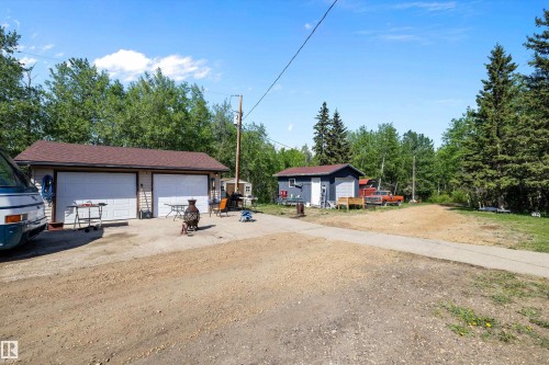 Two-car garage with tan siding and a brown shingled roof, featuring dual white garage doors - 53257 Rge Road 211, Rural Strathcona County, AB - Outdoor