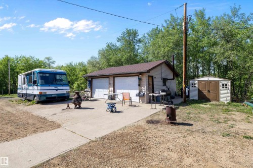 Two-car garage structure with dual white garage doors, a brown shingle roof, and light-colored siding - 53257 Rge Road 211, Rural Strathcona County, AB - Outdoor