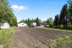 Expansive plot of cultivated land with a backdrop of mature evergreen and deciduous trees - 