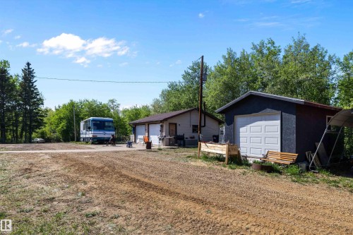 Gravel driveway with two detached structures featuring composition shingle roofs and multiple garage doors - 53257 Rge Road 211, Rural Strathcona County, AB - Outdoor