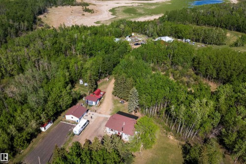Aerial perspective showcasing a residential property surrounded by dense deciduous and coniferous trees, featuring multiple structures with red roofs - 53257 Rge Road 211, Rural Strathcona County, AB - Outdoor With View