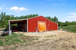Red metal-sided barn featuring a gambrel roofline and an attached covered lean-to area - 