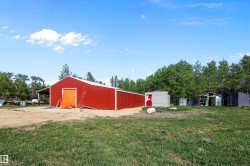 Red metal barn structure with a white roof and an orange fabric door - 