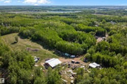 Expansive forested landscape featuring a mix of deciduous and evergreen trees, a large red barn with a white roof, and several smaller outbuildings - 