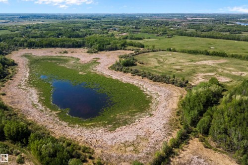 Expansive natural landscape featuring a central water body surrounded by green vegetation and wooded areas - 53257 Rge Road 211, Rural Strathcona County, AB - Outdoor With View