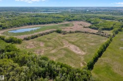 Expansive land parcel with a large pond, surrounded by mature trees and open fields - 