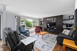 Spacious living area featuring expansive windows, wood-finish flooring, and crown molding - 