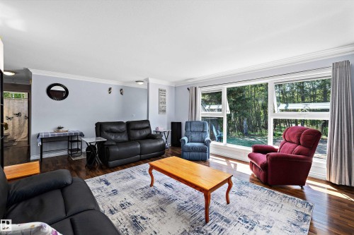 Spacious living area featuring large picture windows, wood-finish flooring, light blue walls, and white crown molding - 53257 Rge Road 211, Rural Strathcona County, AB - Indoor Photo Showing Living Room