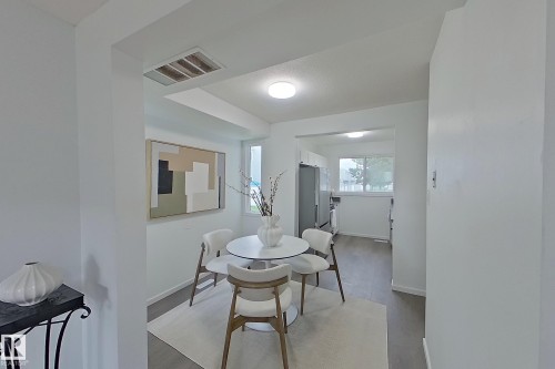 Bright dining area featuring light gray wood-finish flooring and a clean white color palette - 209 Dickinsfield Court Nw, Edmonton, AB 