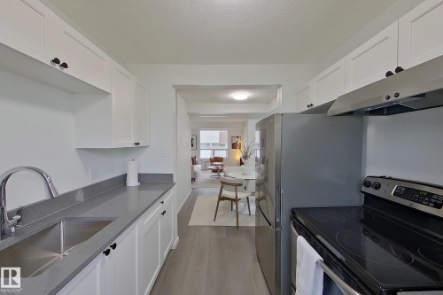 Galley kitchen featuring white cabinetry, grey countertops, and stainless steel appliances - 209 Dickinsfield Court Nw, Edmonton, AB 