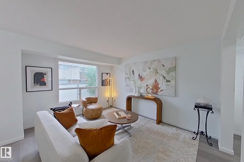 Living area featuring wood-finish flooring, white walls, and a large window - 209 Dickinsfield Court Nw, Edmonton, AB 