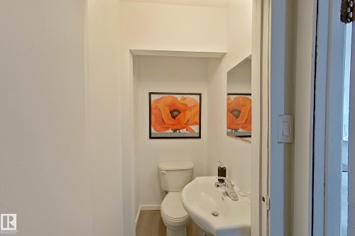 White pedestal sink with chrome faucet, white toilet, and recessed wall shelving - 209 Dickinsfield Court Nw, Edmonton, AB 