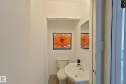 White pedestal sink with chrome faucet, white toilet, and recessed wall shelving - 
