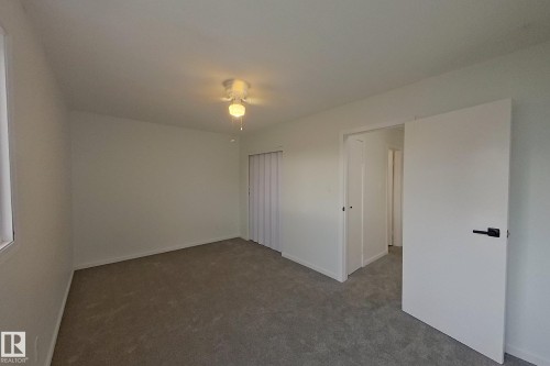 Interior room featuring light gray carpet flooring, white walls, and a ceiling fan with light fixture - 209 Dickinsfield Court Nw, Edmonton, AB 