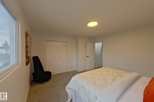 Carpeted room featuring a ceiling-mounted light fixture, a window with white trim, and a bi-fold closet - 209 Dickinsfield Court Nw, Edmonton, AB 