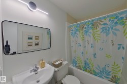 Bathroom featuring a white pedestal sink with chrome faucet, a rectangular mirror, and a white bathtub with a shower curtain - 