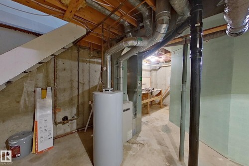 Unfinished basement with concrete flooring, exposed ceiling joists, visible ductwork, and a water heater installation - 209 Dickinsfield Court Nw, Edmonton, AB 