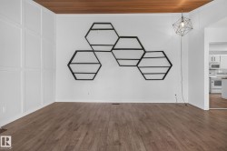 Spacious interior featuring wood-finish flooring, a paneled accent wall, and a wood plank ceiling - 