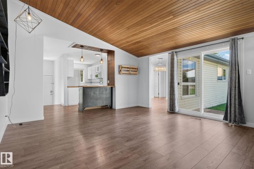 Spacious room featuring wood-finish flooring, a wood-paneled vaulted ceiling, and white painted walls - 1071 Millbourne Road Nw, Edmonton, AB 