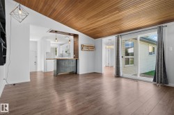 Spacious room featuring wood-finish flooring, a wood-paneled vaulted ceiling, and white painted walls - 