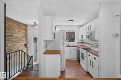 Updated kitchen featuring white cabinetry with matte black hardware, wood-finish countertops, stainless steel appliances, and a window above the sink - 