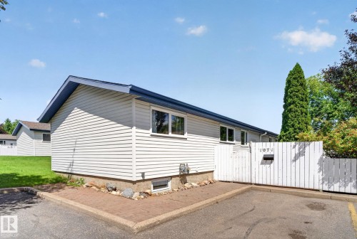Exterior featuring light-colored horizontal siding, a contrasting dark blue roof, and multiple windows - 1071 Millbourne Road Nw, Edmonton, AB 