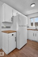 Kitchen featuring wood-finish flooring and white cabinetry with black hardware - 