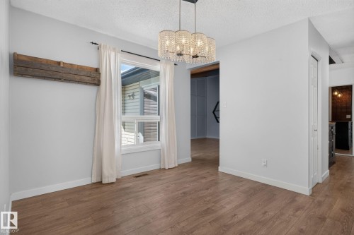 Interior space featuring wood-finish flooring, white baseboards, and a window with white trim and curtains - 1071 Millbourne Road Nw, Edmonton, AB 