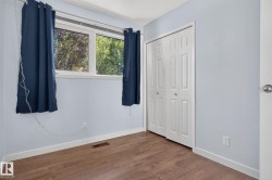 Light-filled interior featuring wood-finish flooring, a double window, and a bi-fold closet door - 