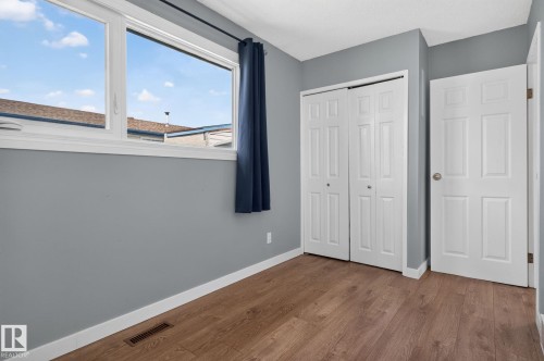 Room featuring wood-finish flooring, a large window with white trim, and light gray walls - 1071 Millbourne Road Nw, Edmonton, AB 