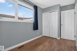 Room featuring wood-finish flooring, a large window with white trim, and light gray walls - 