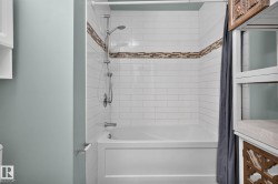 Bathtub with subway tile surround, mosaic accent band, and chrome fixtures - 