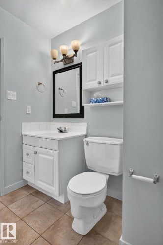 Bathroom featuring a white vanity with built-in cabinetry, a rectangular sink, and a dark-framed mirror - 1071 Millbourne Road Nw, Edmonton, AB 