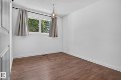 Bright room featuring wood-finish flooring, white walls, and a window with natural light - 