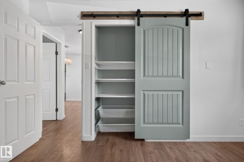 Custom barn door with black hardware, complementing a built-in shelving unit featuring pull-out wire baskets - 1071 Millbourne Road Nw, Edmonton, AB 